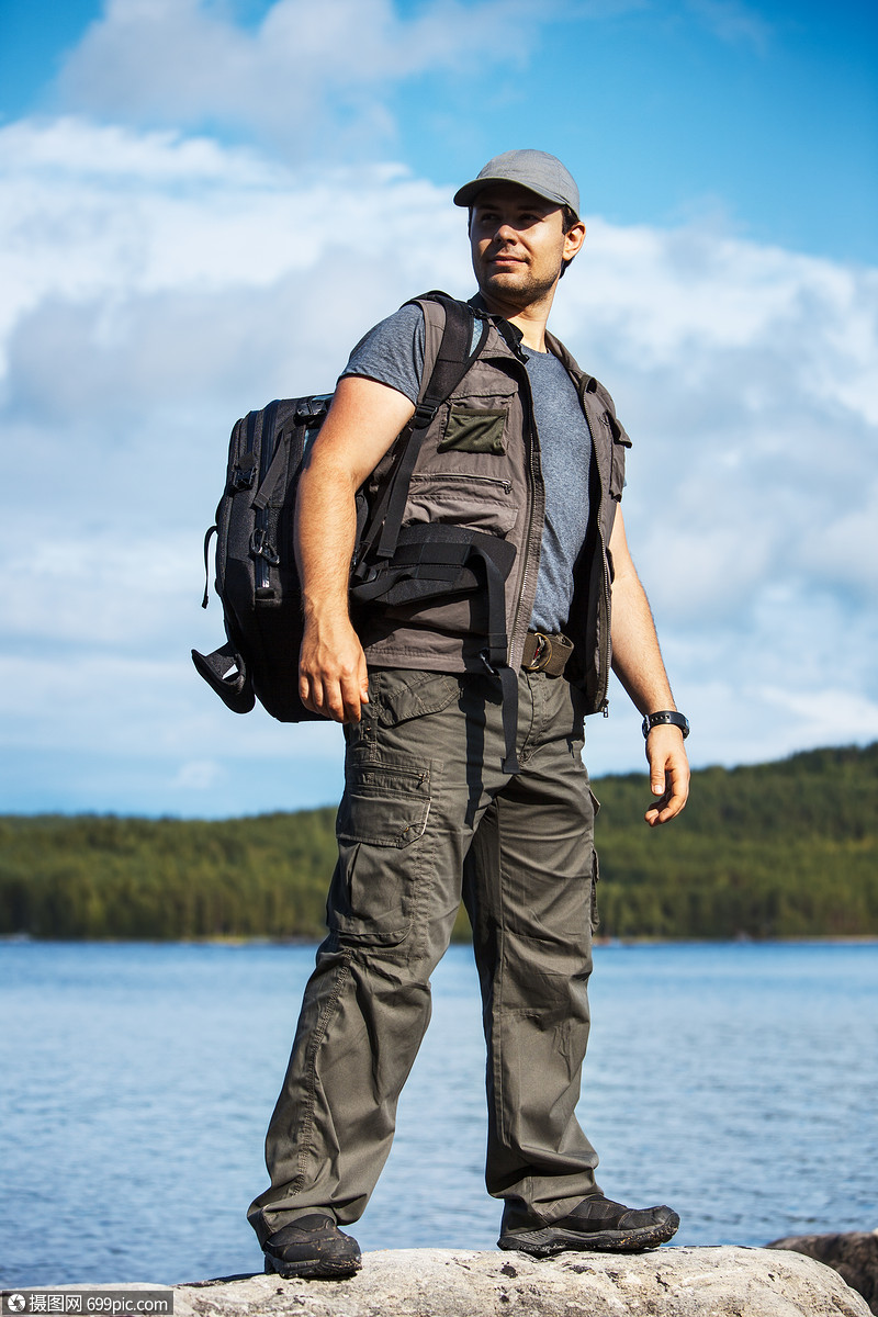 轻人游客背包站湖底的岩石上