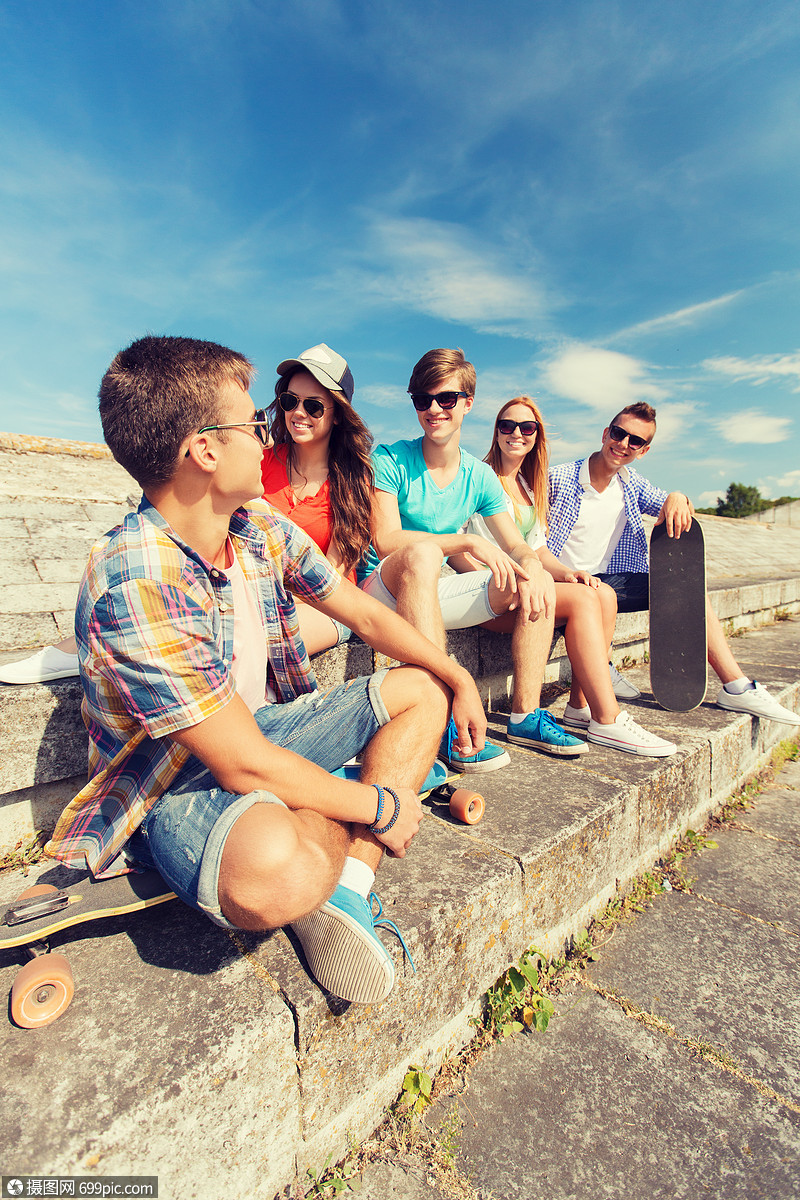 友谊,休闲,夏天人的群微笑的朋友滑板坐城市街道上