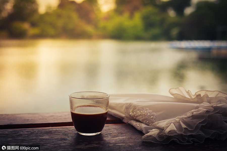 下午,杯咖啡把雨伞放湖边的木桌上杯子春天