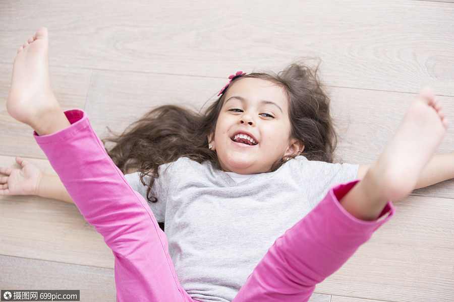 高角度的视角,嬉戏的女孩躺地板上,腿家里抬小孩可爱的