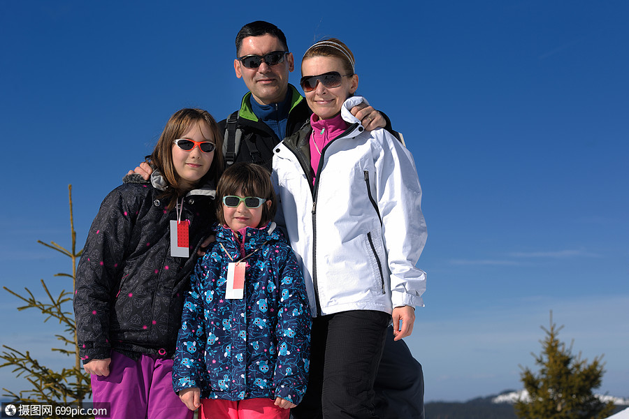 美丽的冬天阳光明媚的日子里,幸福的轻家庭的肖像,背景蓝天雪