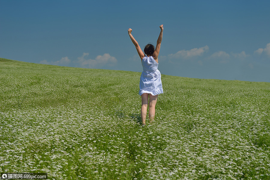 轻快乐的女人绿色的田野,蓝天的背景