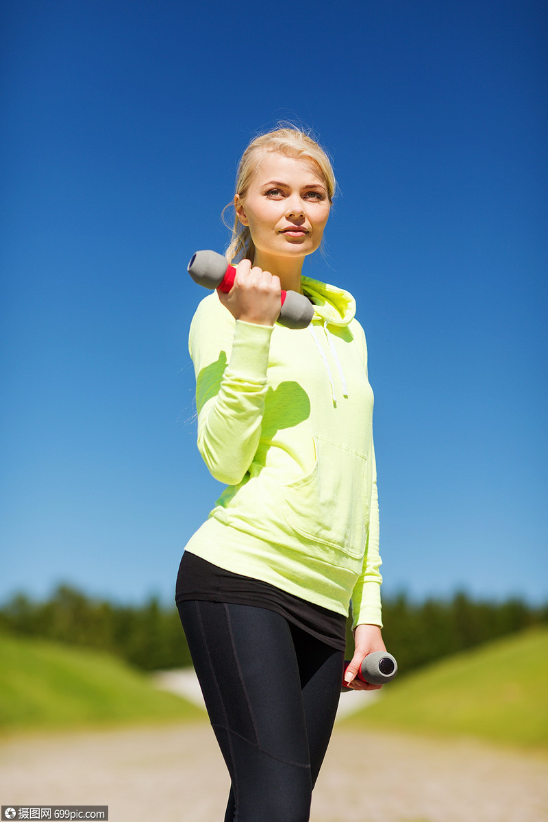 运动生活方式轻的运动女与轻哑铃户外田径运动肌肉