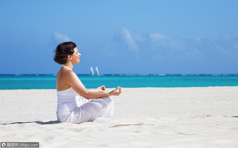 海滩上坐着莲花姿势的快乐女人的冥想瑜伽放松