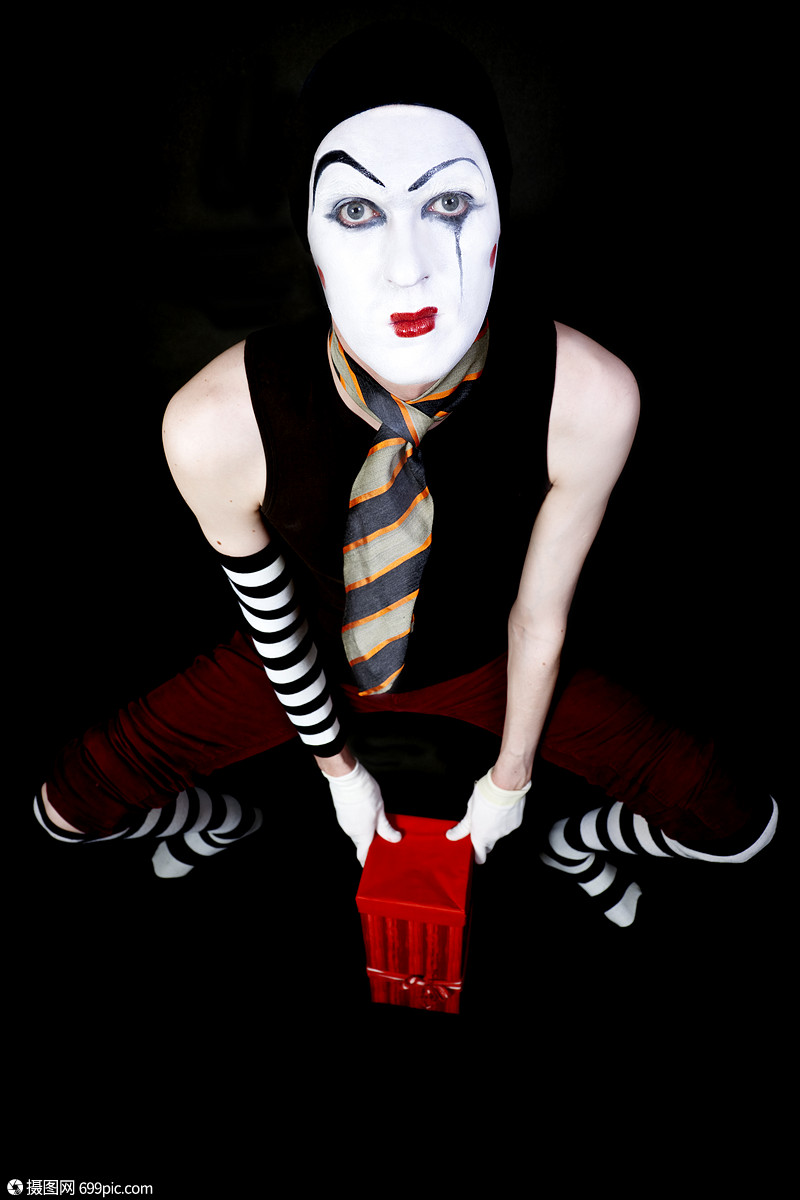 黑色背景上红色礼品盒的哑剧肖像小丑幽默