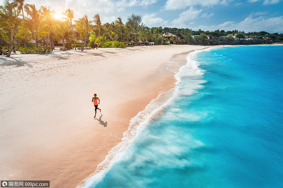 日落时,海边的白色沙滩上,位正奔跑的轻女子的鸟瞰暑假顶级景观的运动