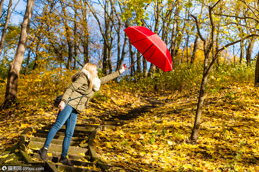 着红色的伞,迎风作战女人带着雨伞公园散步,风很大伍兹行走