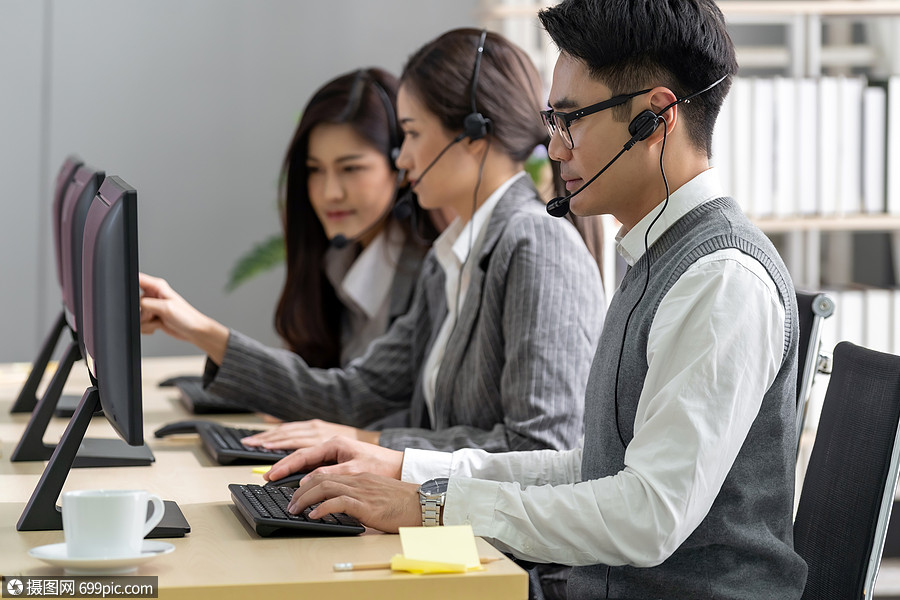 运营商男子代理与耳机工作呼叫中心与他的同事队客户服务技术支持工作