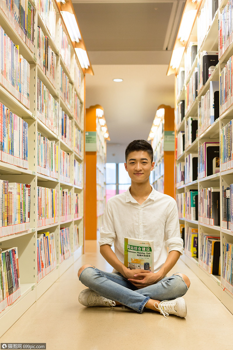 照片 教育文化 坐在图书馆书架旁看书的男生.jpg