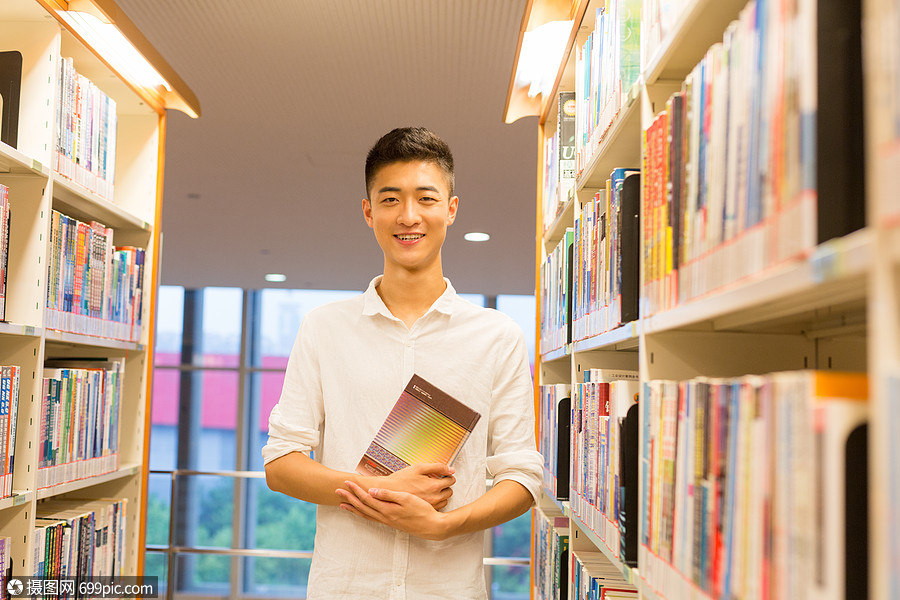 站在图书馆书架旁看书的帅气男同学