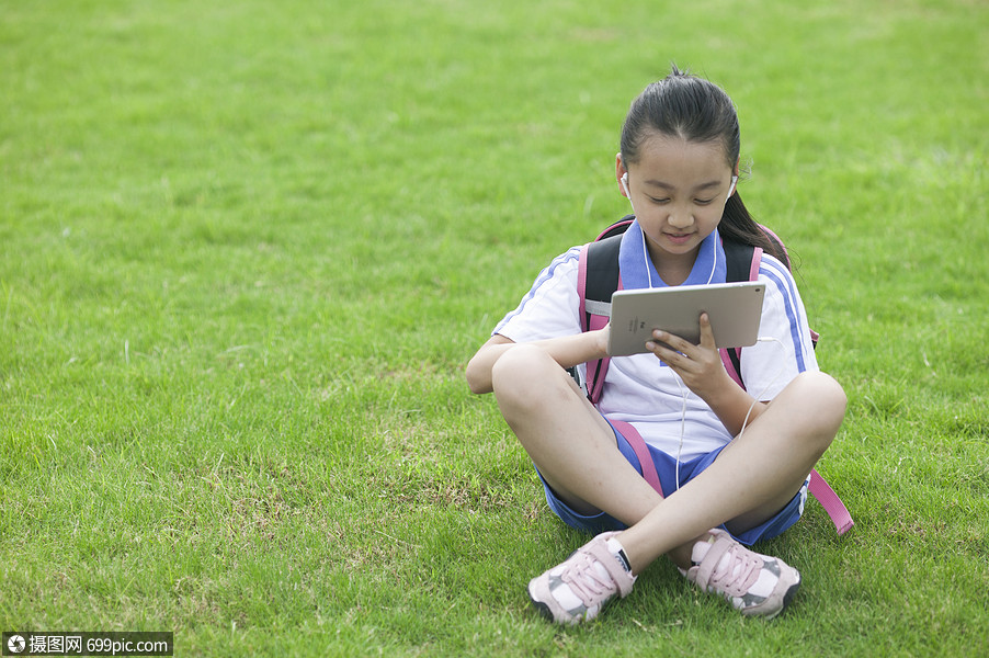 女同学在学校草坪上用ipad学习