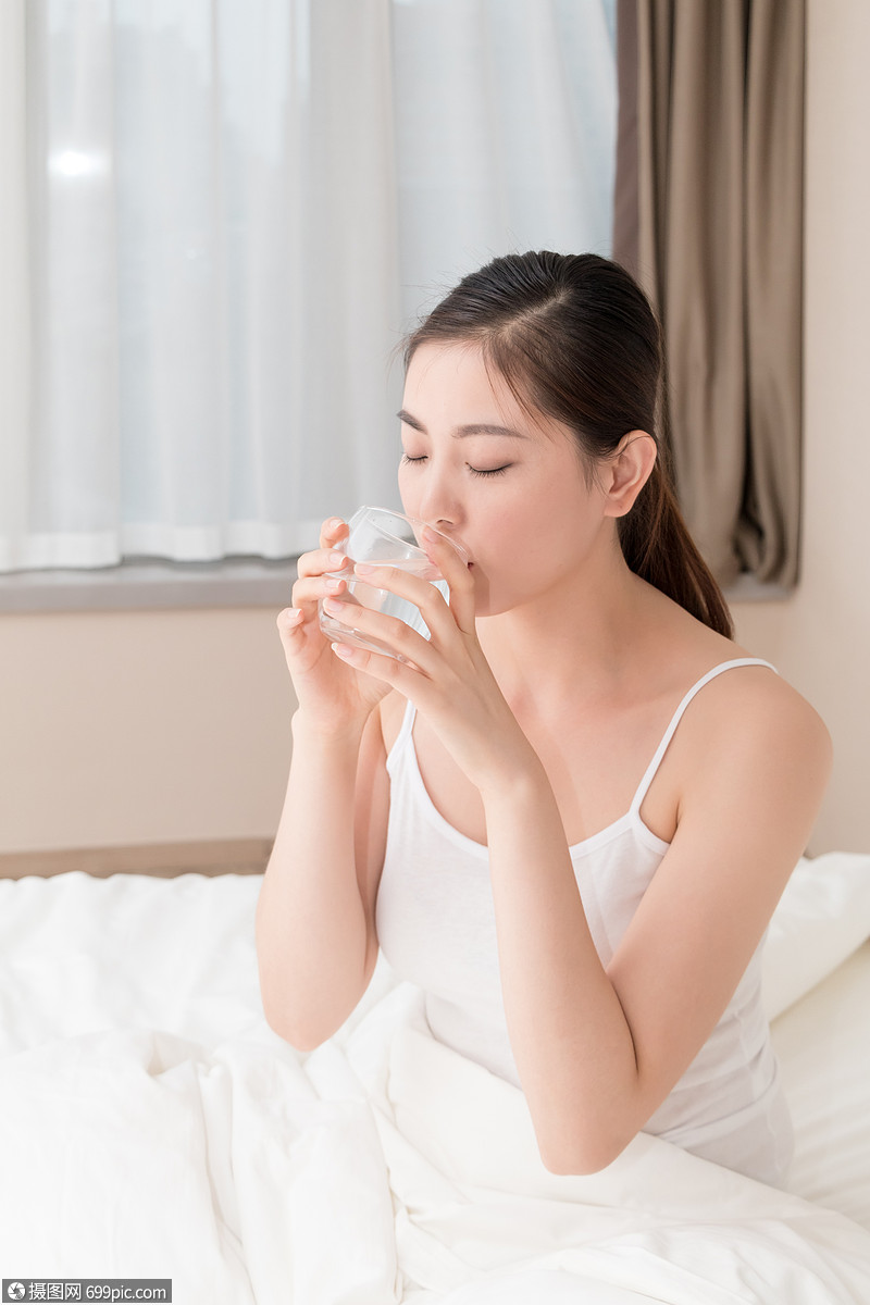 坐在床上喝水的年轻美女特写人物