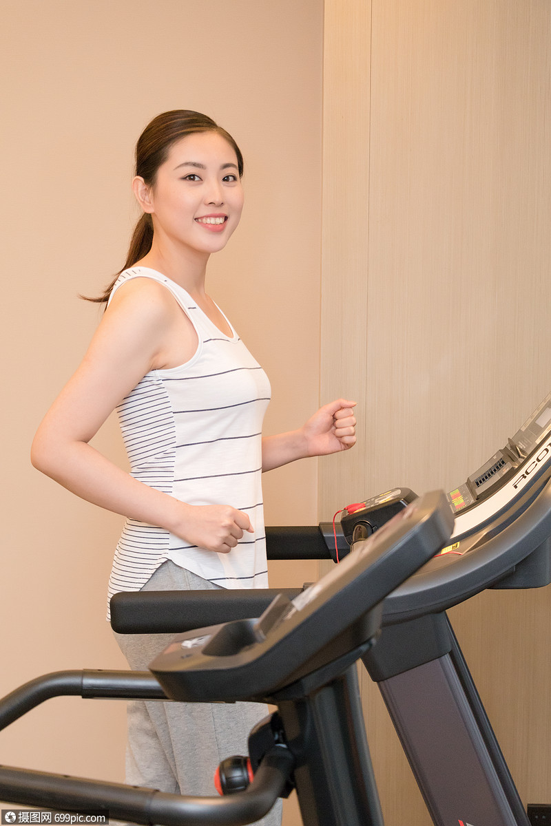 年轻女子在跑步机上运动跑步