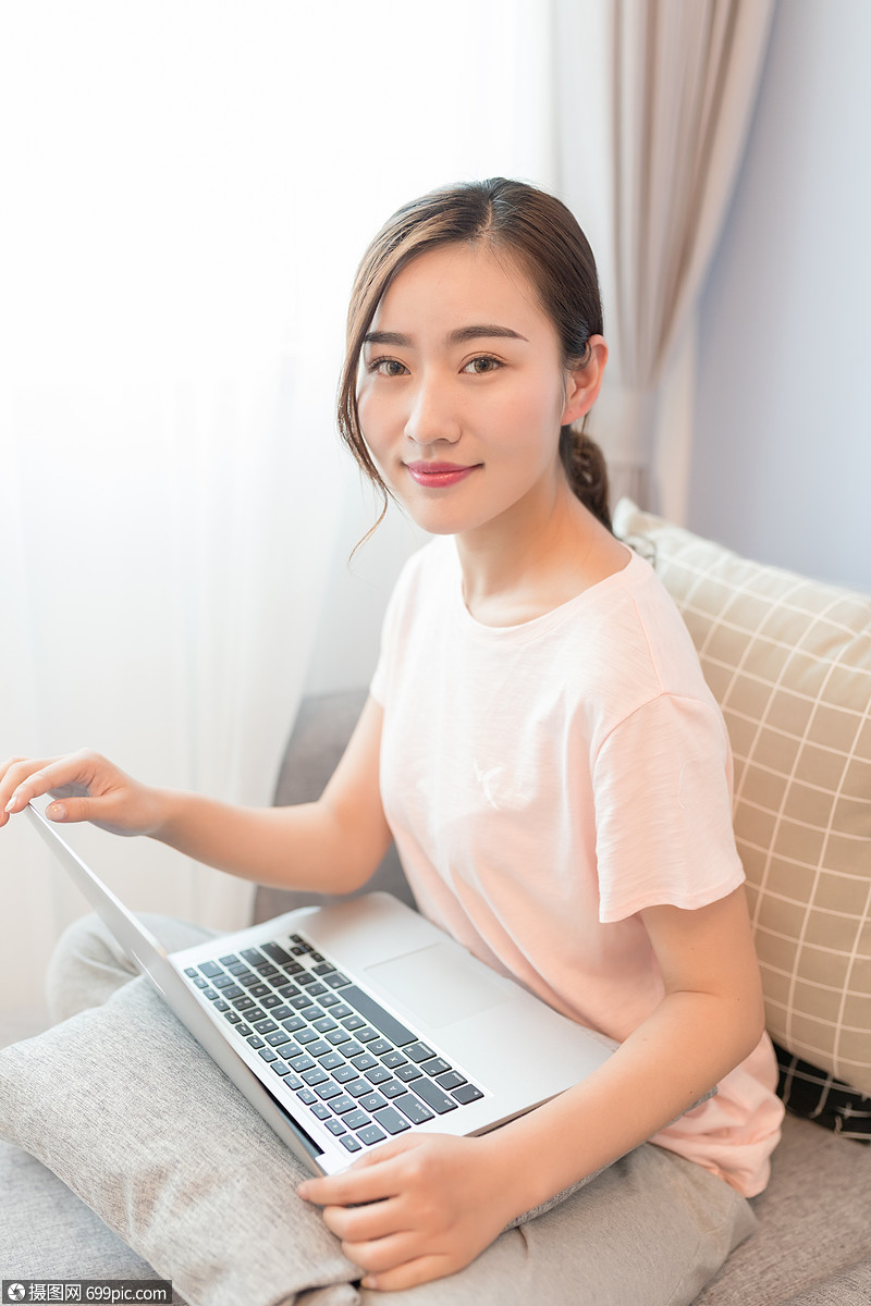 坐在沙发上玩电脑的年轻女性