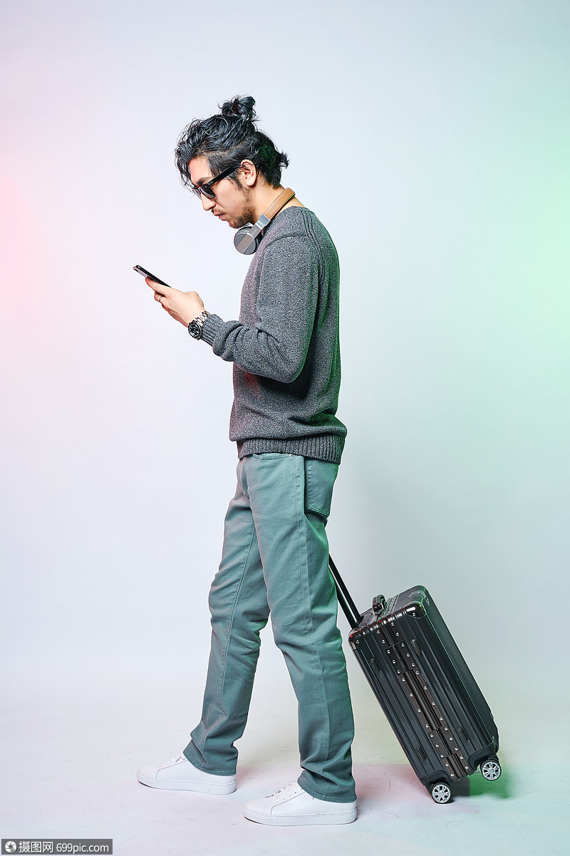 休闲男性色彩创意推着拉杆箱拿着手机