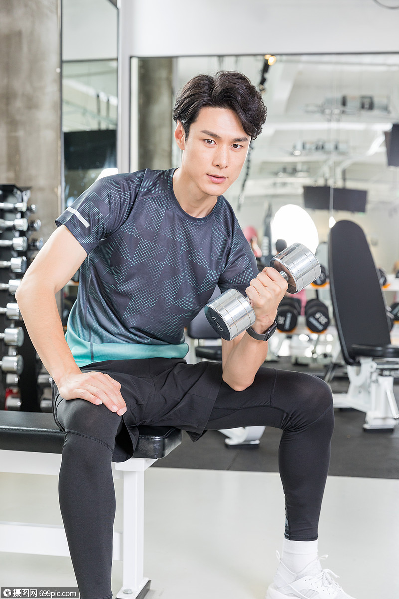 年轻男性健身房举哑铃力量训练