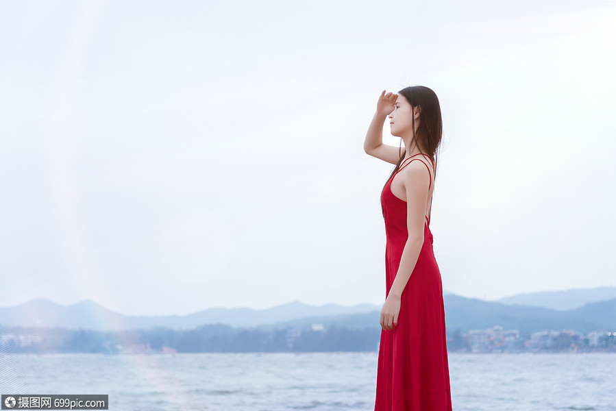 深圳较场尾海边礁石上的红衣少女眺望远方侧影