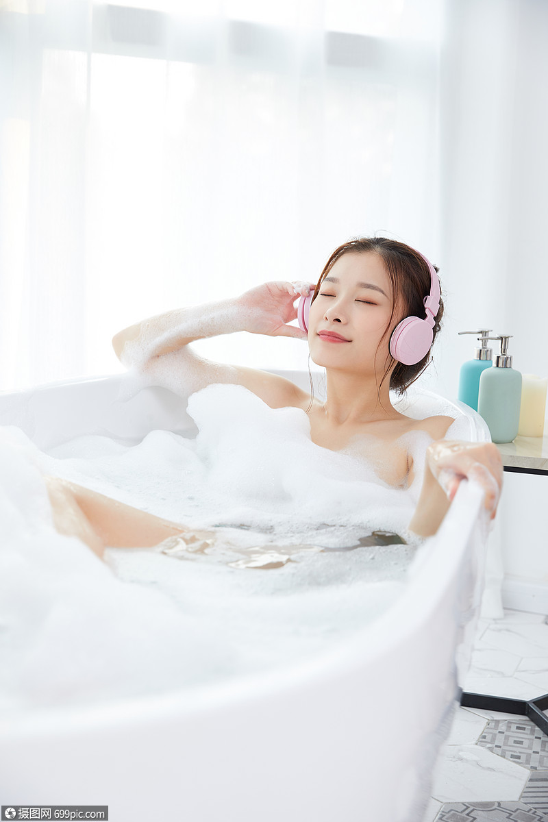 年轻女性洗泡泡浴听音乐