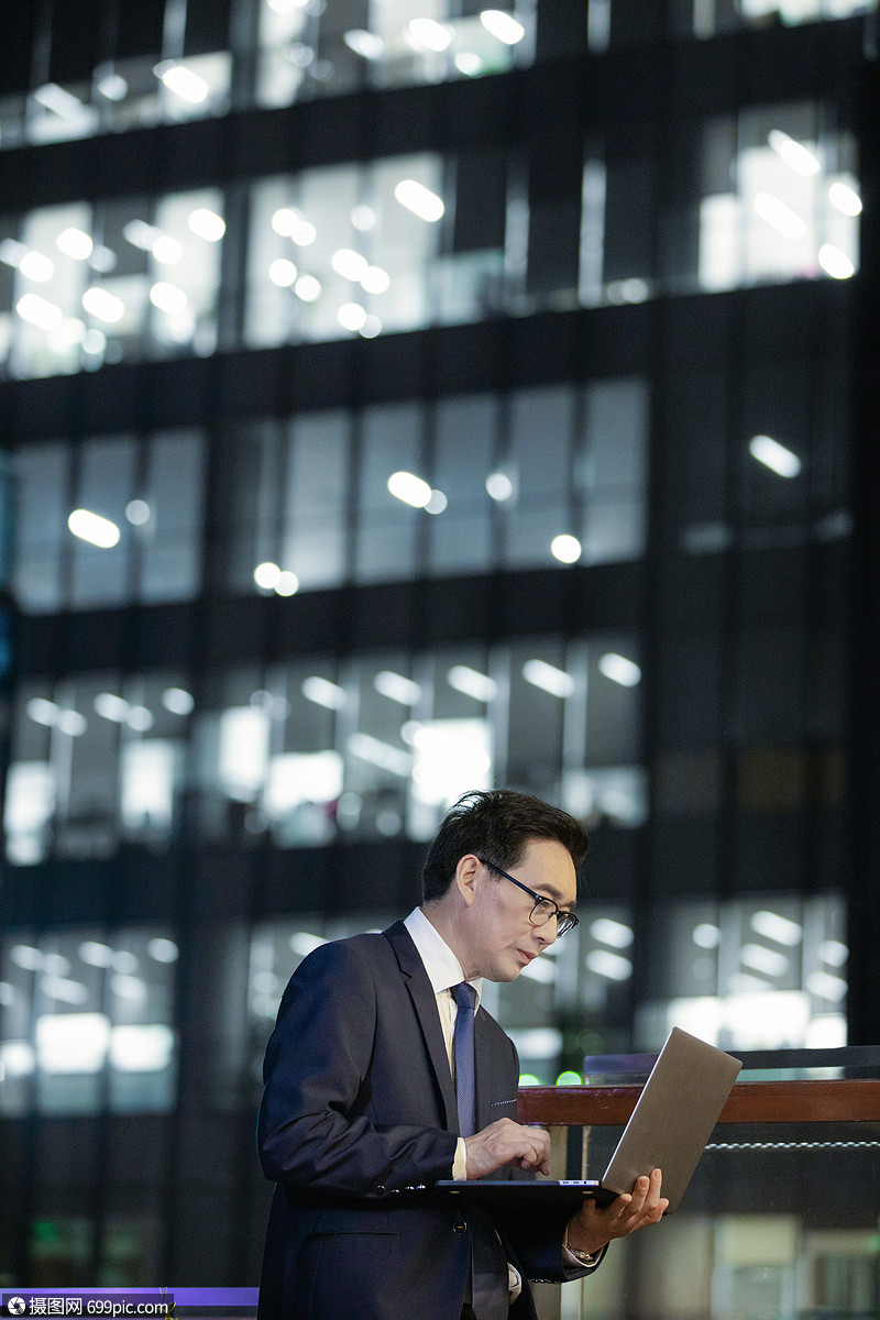 商务男性夜晚在户外拿电脑处理工作职员中国人