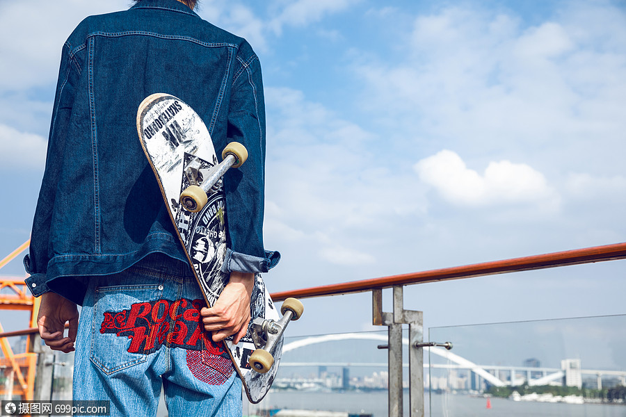 拿着滑板的男孩背影