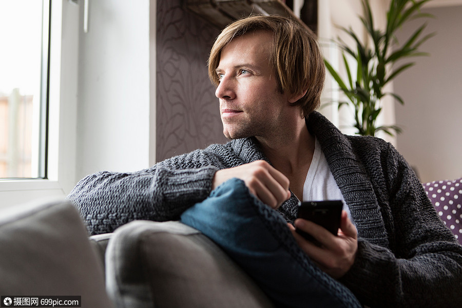 在客厅沙发上使用智能手机的男人外国人外国人像