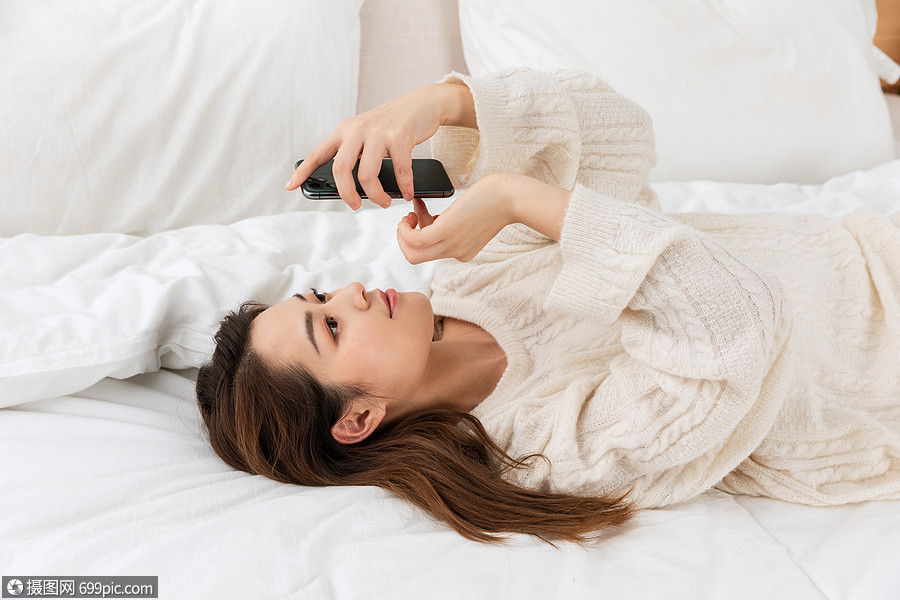 年轻女性躺床上看手机玩手机中国人