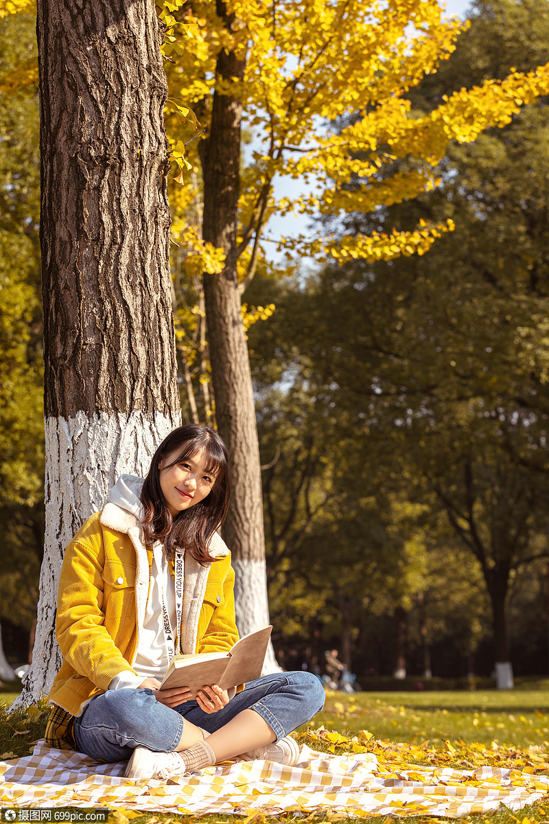 倚靠在银杏树下看书的女孩