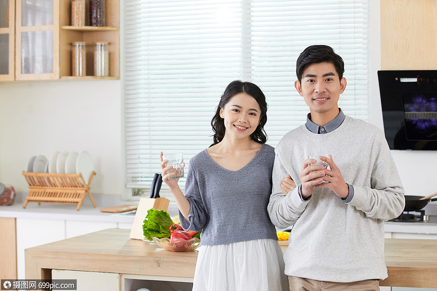 年轻情侣在厨房拿水杯喝水家庭生活