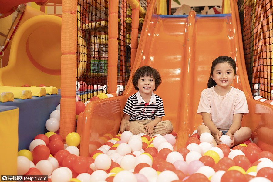 坐在滑梯上嬉戏的小朋友无忧无虑儿童游乐场