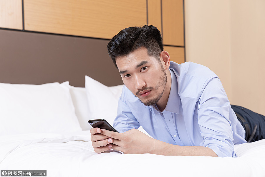 职业男性酒店出差趴床上玩手机