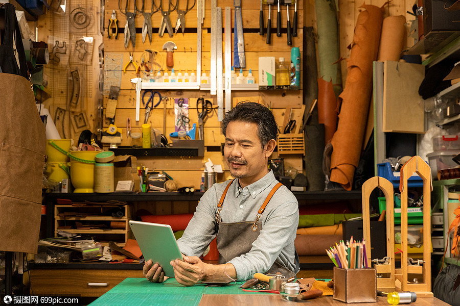 男性皮匠拿平板电脑工作