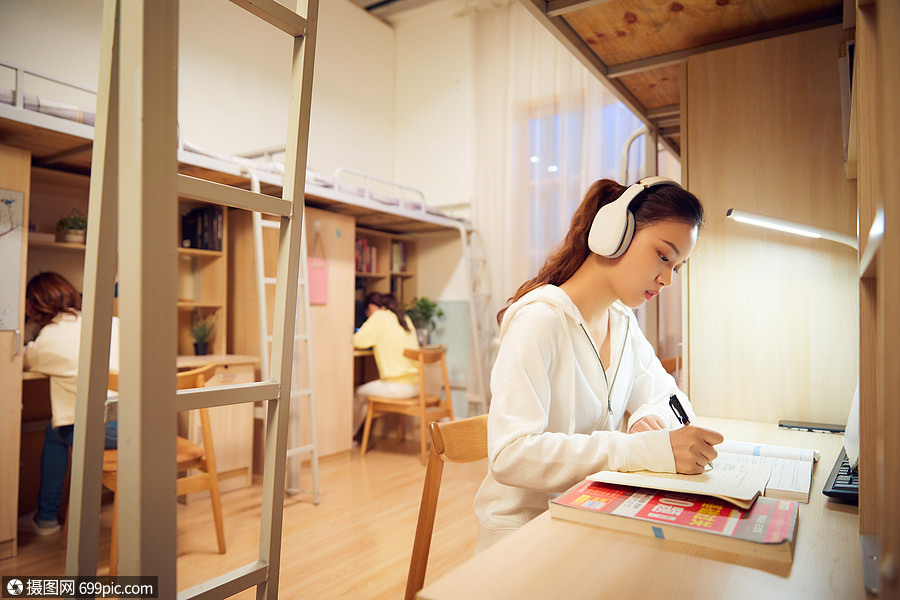 夜晚女学生戴着耳机在宿舍认真复习功课校园生活高中生
