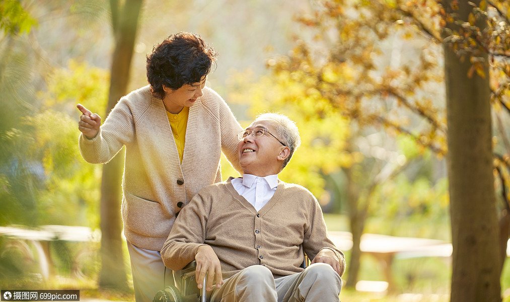 老年夫妇相伴逛公园对视陪伴轮椅