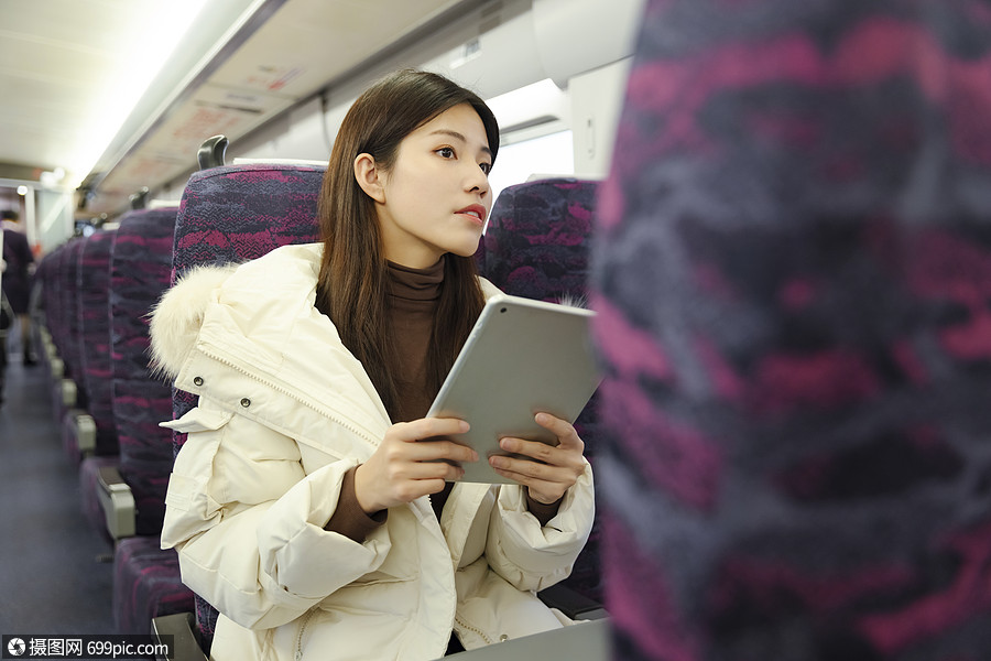 女生在地铁上使用平板电脑