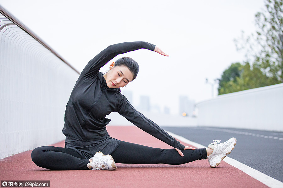 在跑道上做拉伸动作的女性赛道运动衣