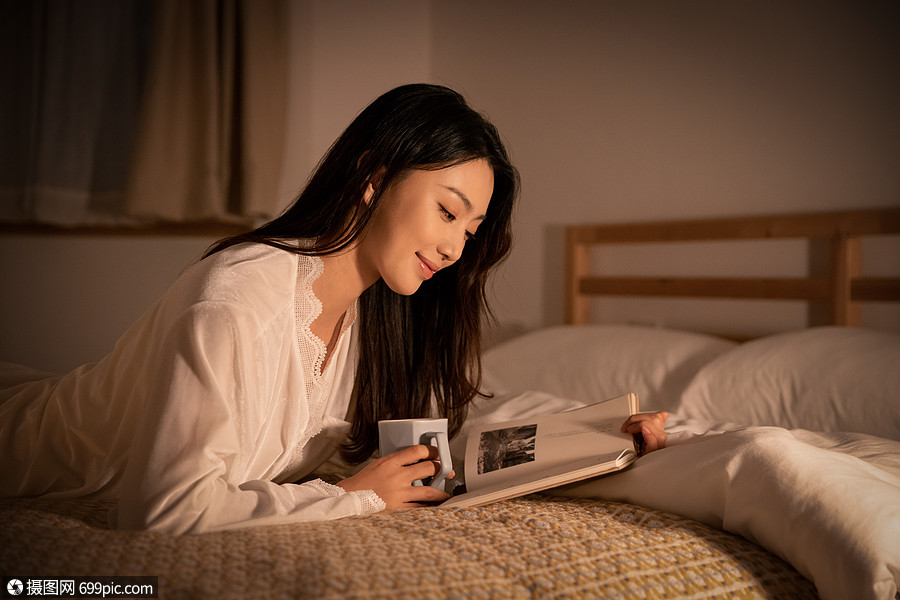 夜晚女性卧室里熬夜阅读看书