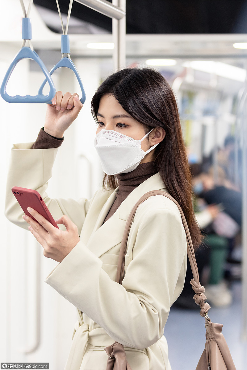 疫情期间下班回家的女性在地铁低头看手机