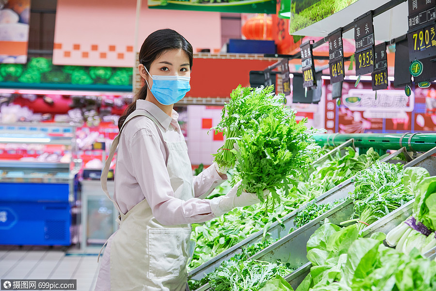 佩戴口罩的超市服务员整理蔬菜区防护商店
